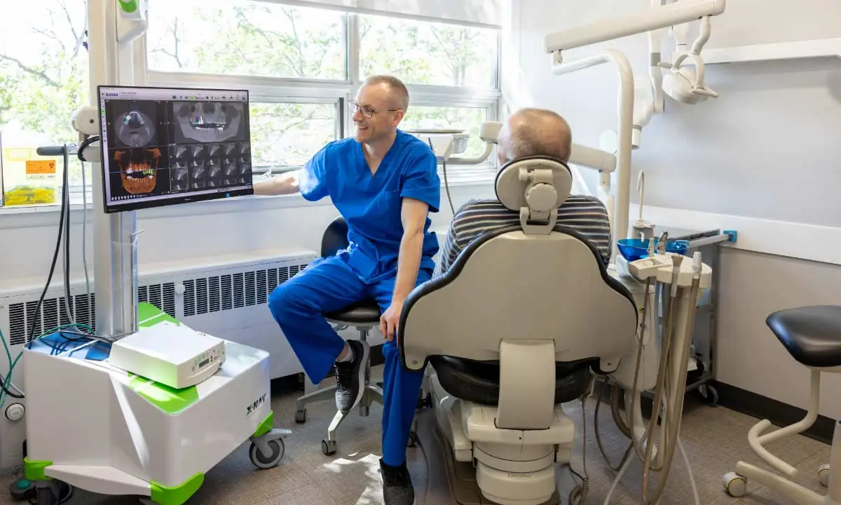 Dr. Devon Laatsch performing emergency dentistry for a male patient sitting in dental chair